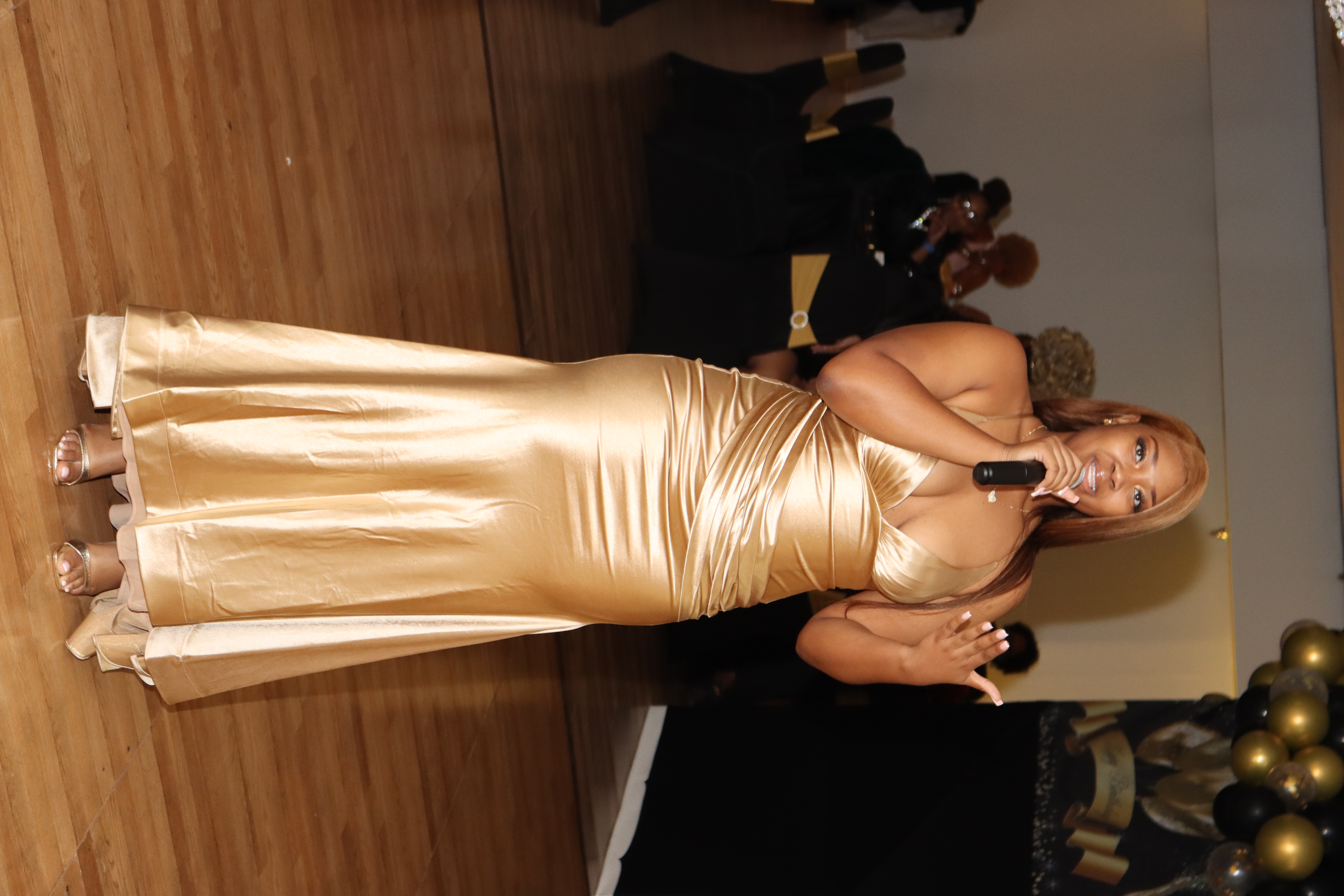 Event speaker in gold gown at a Media Circle covered celebration in Lithonia, GA